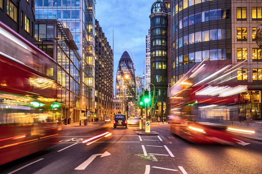 Een foto met trage sluitertijd van de Gherkin in Londen, 's nachts gemaakt met twee Londense bussen die voorbij rijden.