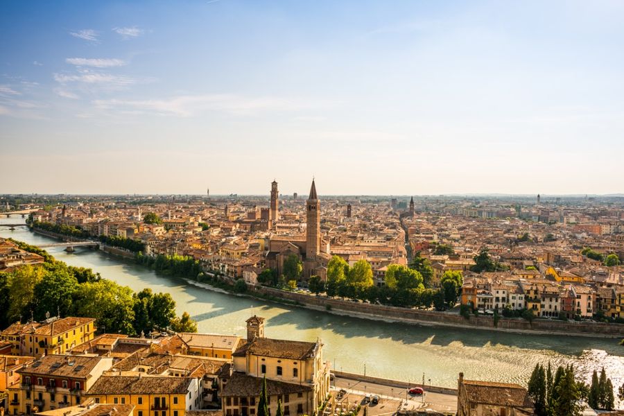 Een foto van de daken van Verona en de rivier die door de stad stroomt, genomen op een heldere en zonnige dag.
