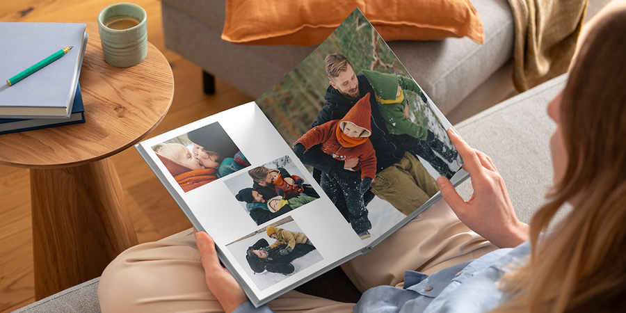 Een vrouw bekijkt een layflat fotoboek van albelli met familiefoto's in de sneeuw, een inspirerende manier om een fotoalbum of fotoboek te maken.