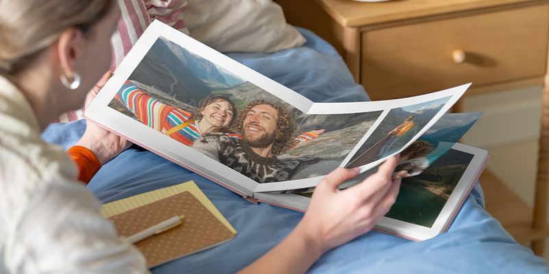 albelli fotoboek inspiratie: een vrouw bekijkt een open fotoboek met een dubbele pagina van een stel in een bergachtig landschap.
