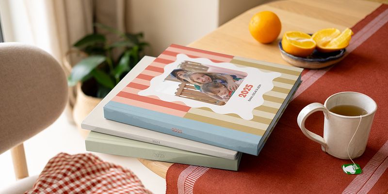 Een stapel kleurrijke, van patronen voorziene albelli Jaarboeken en jaarboek fotoalbums op een salontafel.