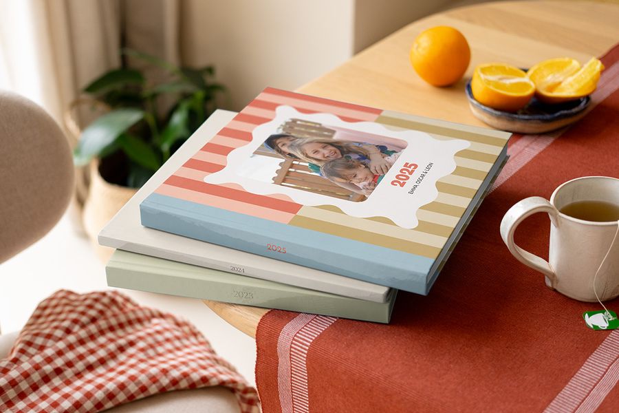 Een stapel kleurrijke, van patronen voorziene albelli Jaarboeken en jaarboek fotoalbums op een salontafel.