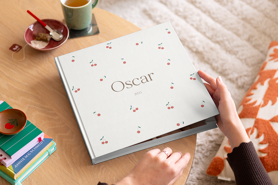 Een vrouw die op het punt staat om een mijn eerste fotoboek van albelli te openen op een houten salontafel.