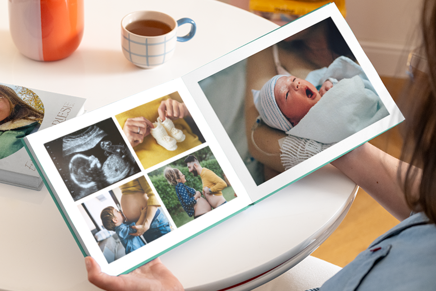 Een open baby fotoboek eerste jaar met een zwangere buik, echo en babyschoentjes op de linkerpagina, en een foto van een pasgeboren baby op de rechterpagina.