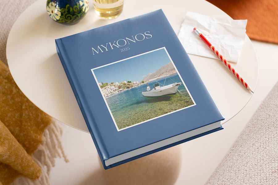Ideeën voor wat te schrijven in een fotoalbum getoond op een Mykonos 2025 reisboek, met een potlood om herinneringen en fotoboek quotes op te schrijven.
