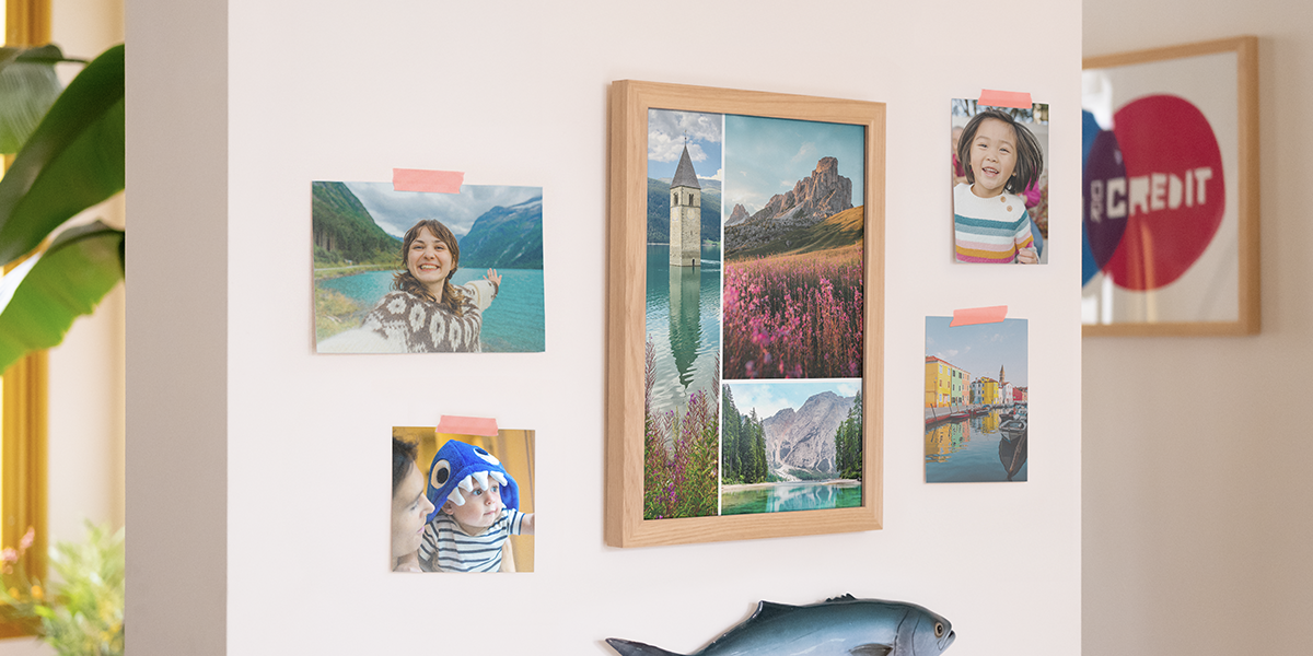 albelli foto afdrukken aan een muur in huis, met een grote lijst vol landschapsprints en vier losse familiefoto’s aan de wand, als inspiratie voor foto afdrukken en foto’s online bestellen.