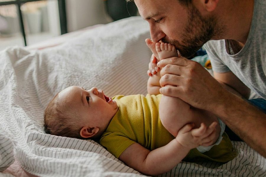 Een vader kust de voetjes van zijn baby, als inspiratie voor een eerste vaderdag kaart en een lieve tekst voor een vaderdag kaart.