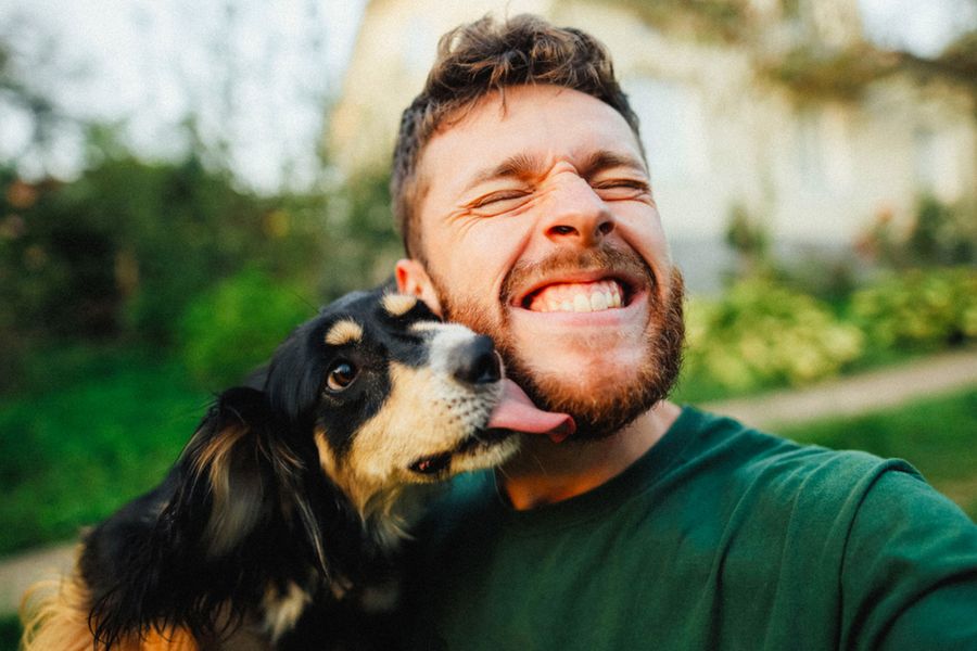 Een man glimlacht met zijn hond, als inspiratie voor een vaderdag kaart en een leuke tekst voor een hondenpapa.