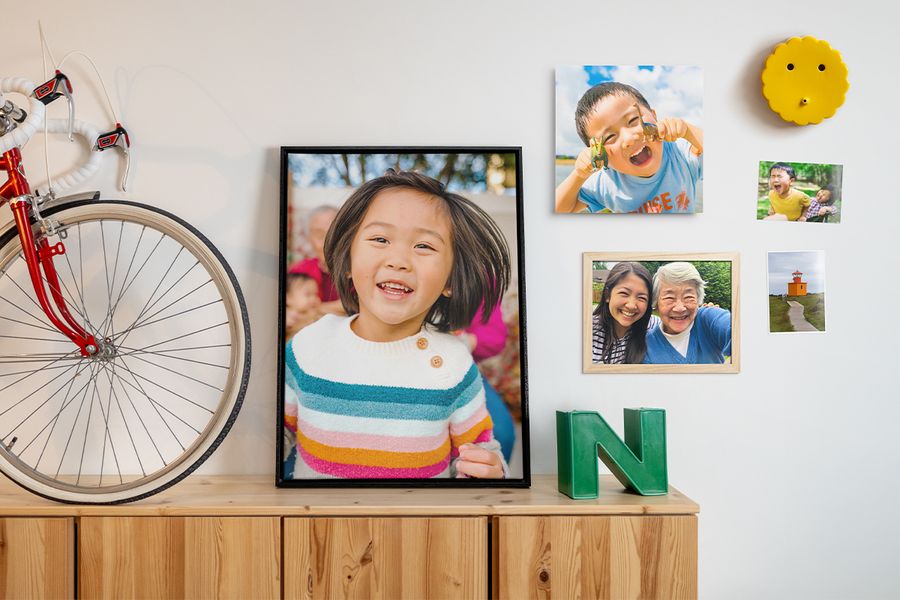 Verschillende familiefoto’s hangen in diverse opstellingen aan de muur naast woondecoratie en wandhangers, als inspiratie voor fotowand decoratie en een frisse update van je interieur.