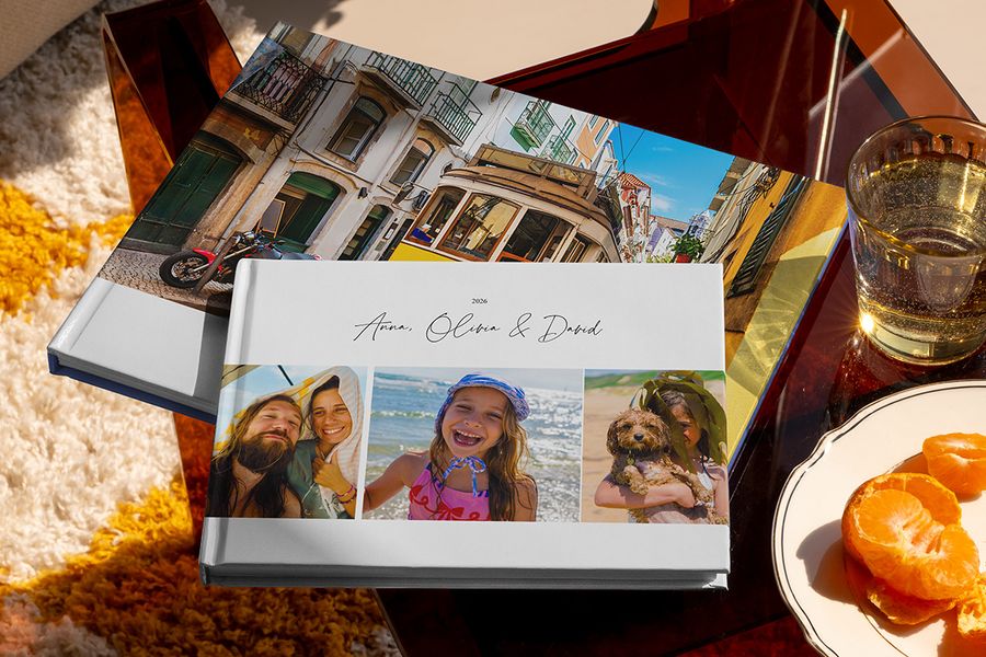 Twee verschillende albelli reisfotoboeken liggen samen in beeld, waaronder een liggend vakantie fotoboek met familiereisfoto’s op de cover en een ander met een vakantiefoto van een tram, als inspiratie voor verschillende soorten vakantie fotoboek maken.
