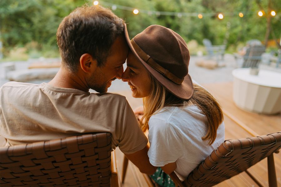 Een man en een vrouw zitten knus tegen elkaar aan in een tuin versierd met lichtjes, een romantisch moment uit albelli's tips voor een vakantie thuis met je partner.