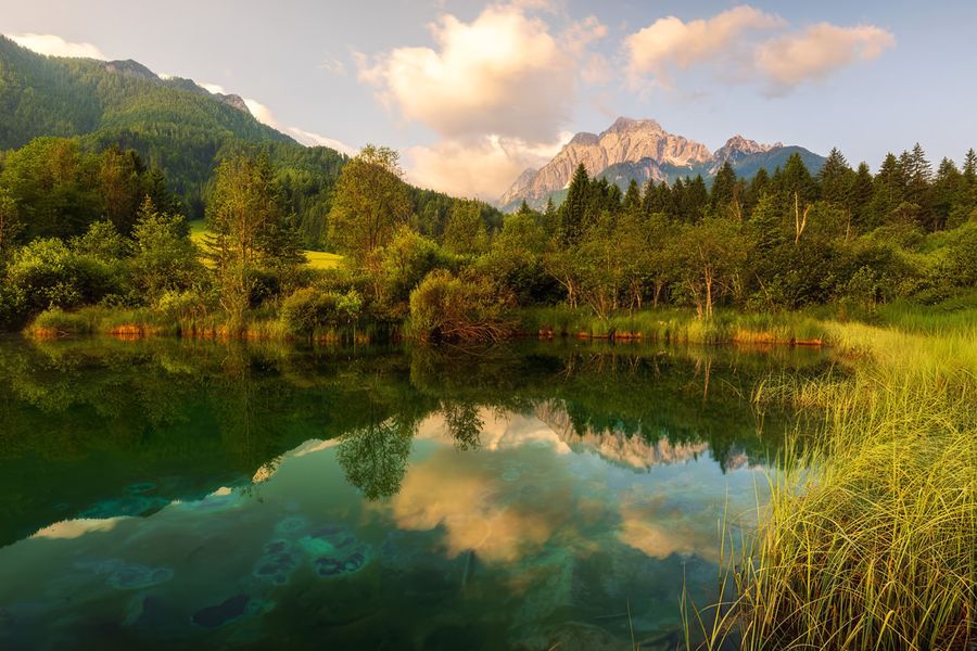 Hoge kalksteenpieken en het heldere, spiegelende water van het Bohinjmeer in Nationaal Park Triglav in Slovenië, een van de beste natuurparken van Europa uit albelli's gids.