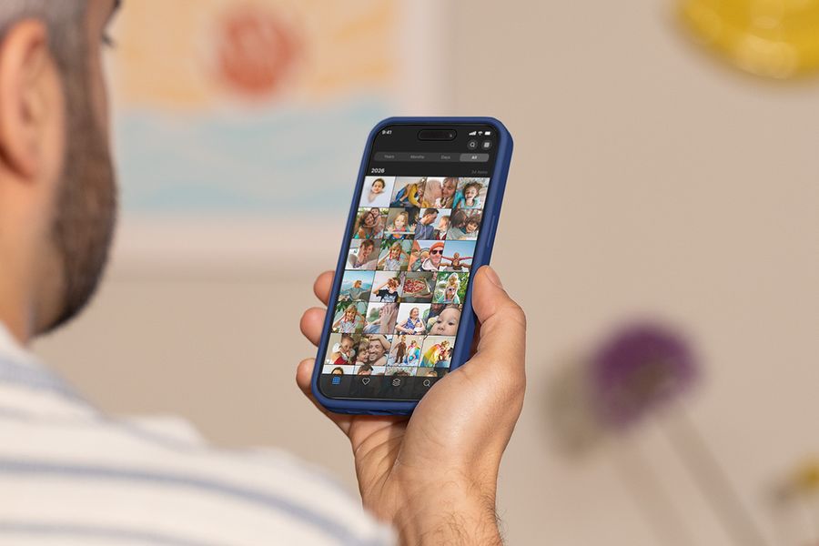 Een man houdt zijn telefoon omhoog en scrolt door zijn camerarol, ter illustratie van albelli's gids voor de beste tools om foto's te organiseren.