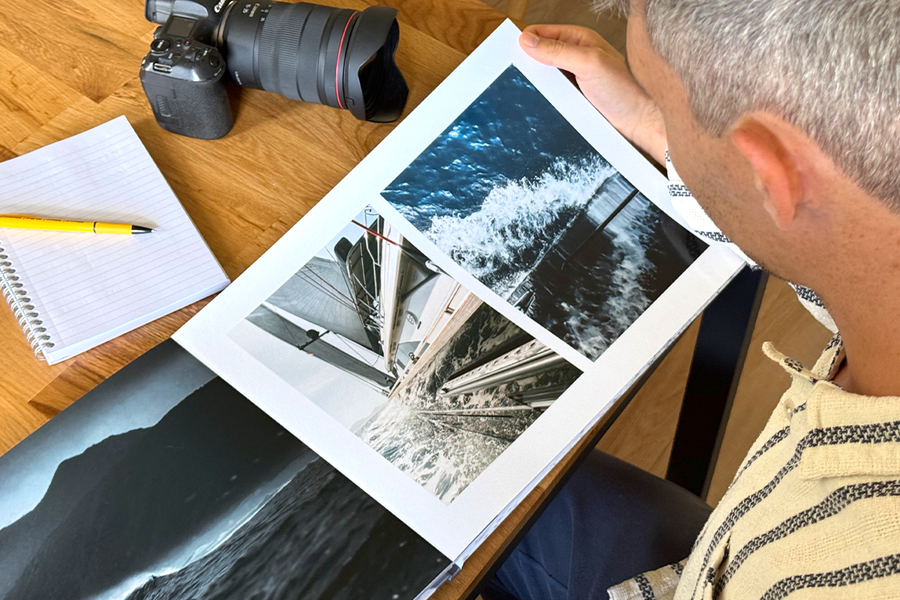 Fotograaf Charl van Rooy kijkt naar zijn portfolio, met zijn camera en een notitieboekje naast hem op de tafel, ter illustratie van albelli's tips voor het kiezen van de beste templates en lay-outs voor een fotografieportfolio.