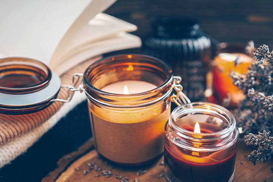 Een paar brandende kaarsen staan naast een takje bloemen, ter illustratie van hoe kaarsen bijdragen aan een gezellige herfstsfeer in albelli's hygge-decoratietips.