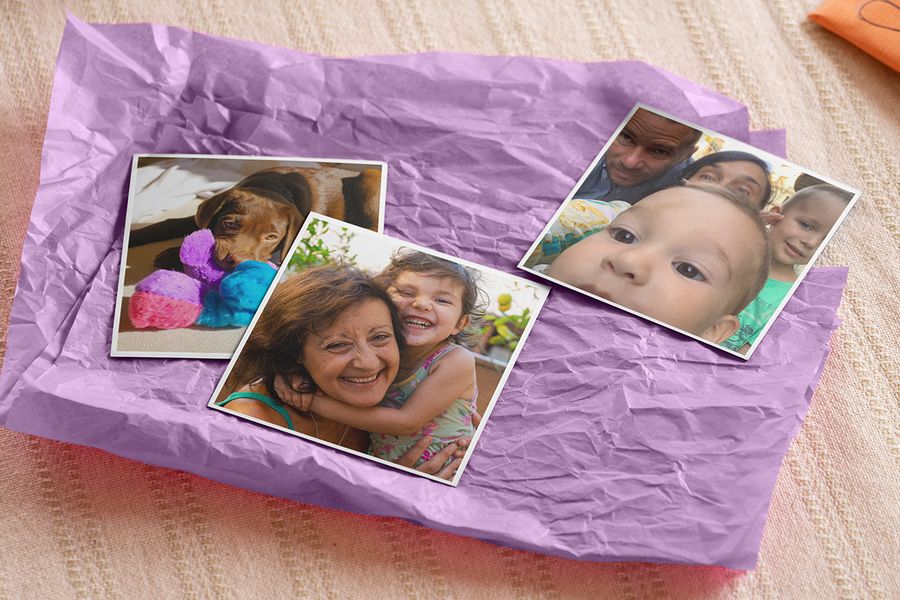 Drie gedrukte foto’s op verfrommeld lila zijdepapier: een puppy met gekleurde speeltjes, een oudere vrouw die een lachend kind knuffelt en een gezin met een baby, ter illustratie van albelli’s gepersonaliseerde fotomagneten om in de Sinterklaasschoen te leggen.