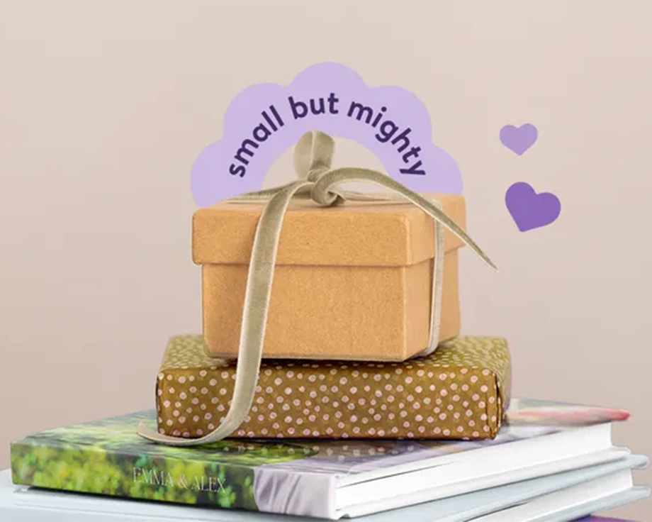 Een stapel albelli fotoboeken met bovenop een ingepakt cadeau, als inspiratie voor gepersonaliseerde kleine cadeaus en doordachte fotocadeau-ideeën.