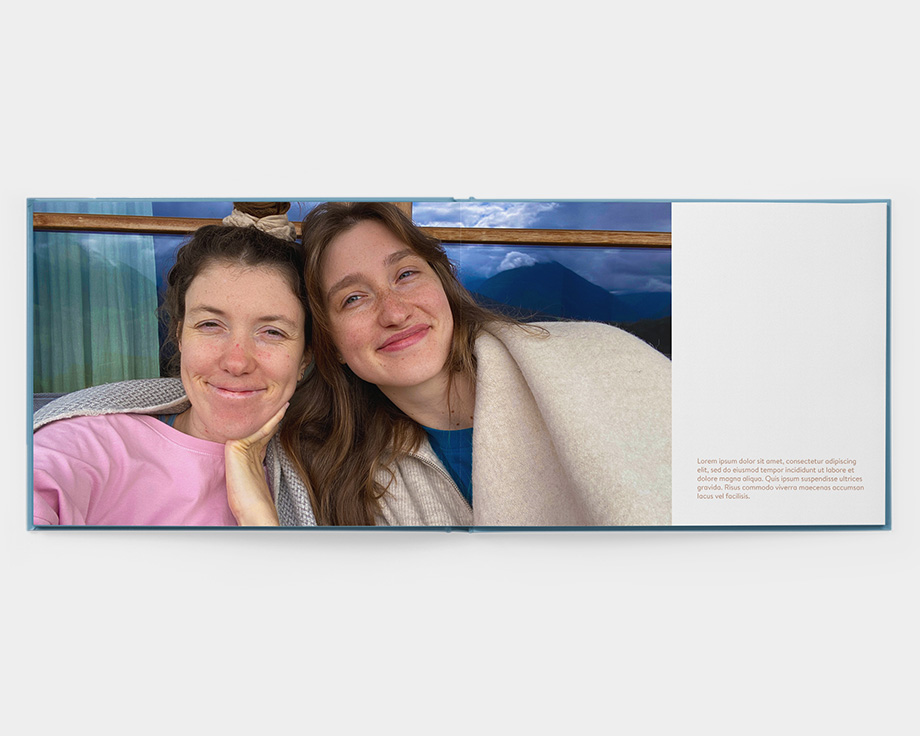 Een fotoboek met premium platliggende pagina's in open landschap met een foto van twee lachende vrouwen
