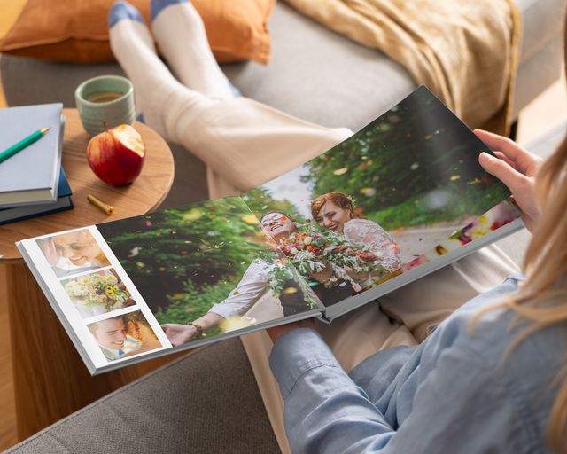 Een vrouw kijkt naar trouwfoto's in een open fotoboek met premium platliggende pagina's.